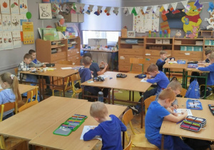 Widok na całą klasę , dziexi siedzą i malują obrazki.